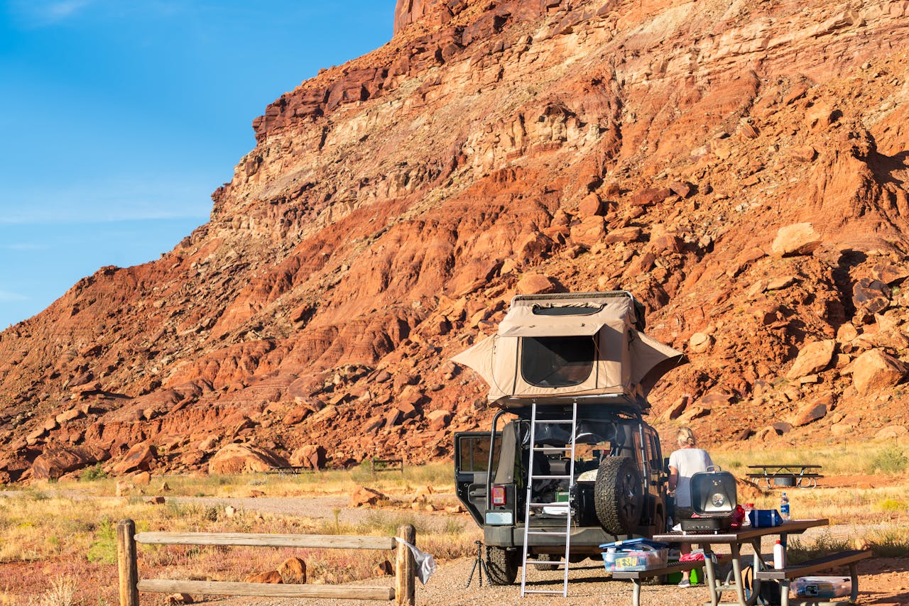 Services Explore the rugged beauty of Utah's desert with a campsite set against stunning red rock cliffs.